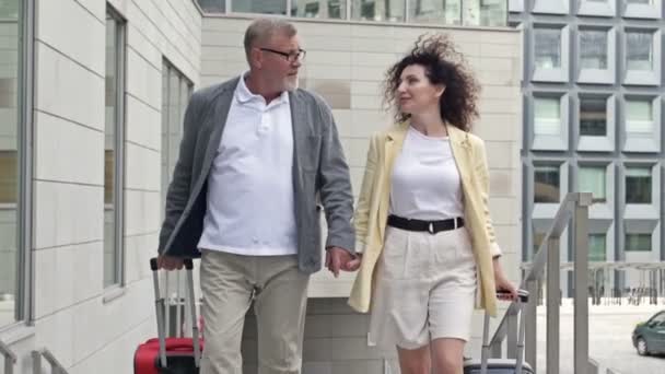 Volwassen echtpaar met koffers loopt door het station, hand in hand. Geweldige vakantie stemming. — Stockvideo