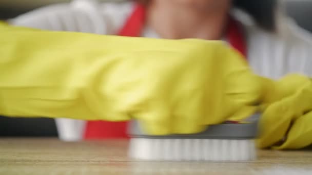 Jonge huisvrouw in geel rubber handschoenen schrobt een vlek op het aanrecht met inspanning. — Stockvideo