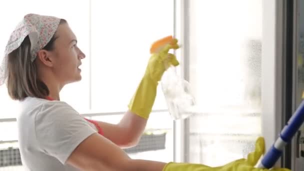 Bela jovem dona de casa lava as janelas e danças. — Vídeo de Stock