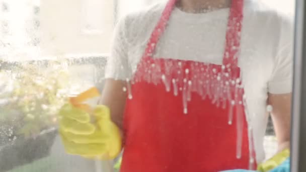 Kvinnliga händer i gula handskar rengöringsfönster ruta med trasa och sprayrengöringsmedel. Tvättfönster med spray. — Stockvideo