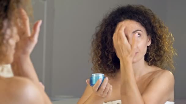 Mujer madura bien arreglada sosteniendo tarro de crema de piel para la cara. Mujer feliz aplicando crema hidratante anti-envejecimiento y mirando a la cámara. Belleza y tratamiento antienvejecimiento. — Vídeos de Stock