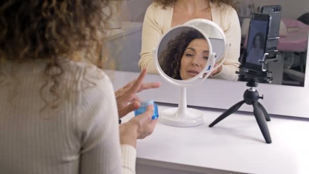 Alegre blogger femenina está mostrando productos cosméticos mientras graba video y da consejos para su blog de belleza. — Vídeos de Stock