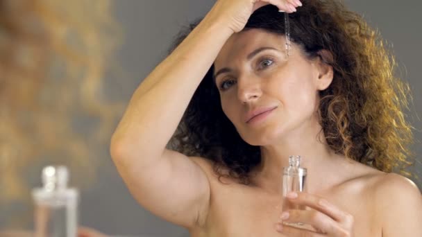 샤워 를 한 후아름답고 성숙 한 여인 이 얼굴에 피펫 으로 화장품 혈청을 바르라. 화장품 과 노화 방지 치료법. — 비디오