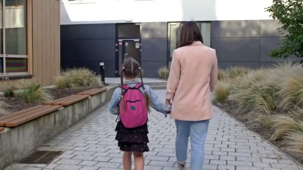En liten flicka med skolväska eller väska som går till skolan med mamma. Tillbaka till skolan. — Stockvideo