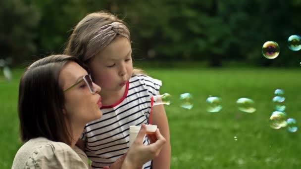 A fiatal nő és a 6 éves lánya szivárvány szappanbuborékokat fújnak. Szórakoztató családi nyaralás. — Stock videók