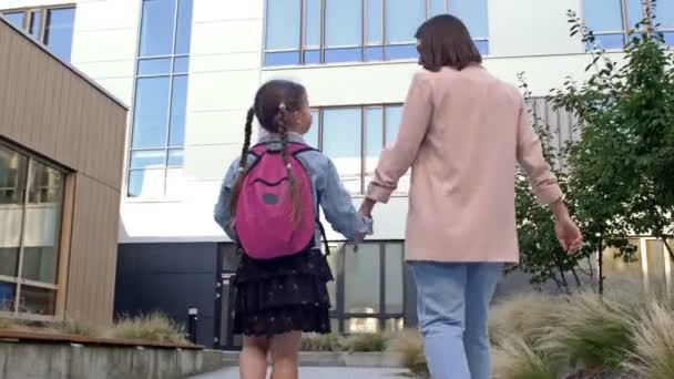 En liten flicka med skolväska eller väska som går till skolan med mamma. Tillbaka till skolan. — Stockvideo