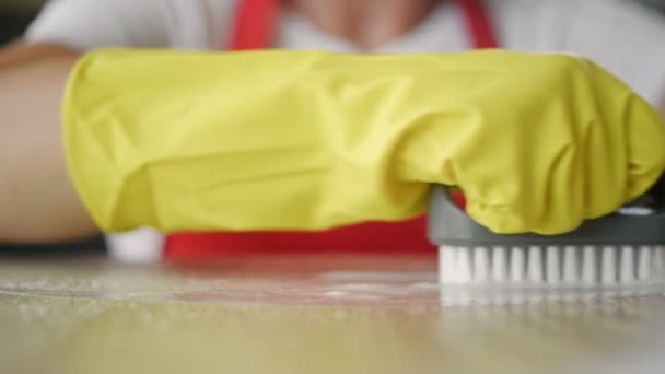 Vrouwen handen in geel rubber handschoenen met moeite schrobben een vlek. — Stockvideo