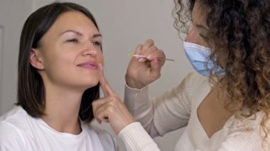 Profesyonel kozmetik uzmanı üst dudağındaki hastalara balmumu epilasyonu uygular..