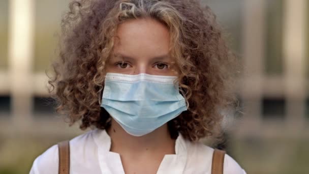 Retrato de una colegiala con una máscara protectora. Primer plano. — Vídeos de Stock