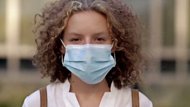 Retrato de una colegiala con una máscara protectora. Primer plano. — Vídeos de Stock