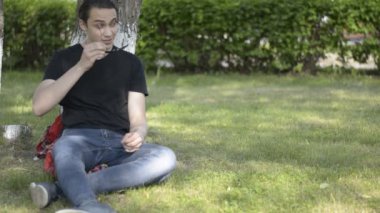 Ağaç ve güneş gözlüğü üzerine koyar parkta oturan çekici genç adam