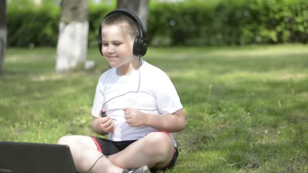 Pojke lyssna på musik på hörlurar och uttrycker glada känslor. — Stockvideo