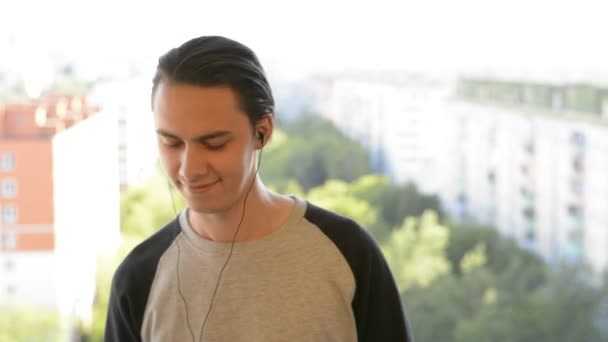 Jovem atraente ouvindo música em fones de ouvido — Vídeo de Stock