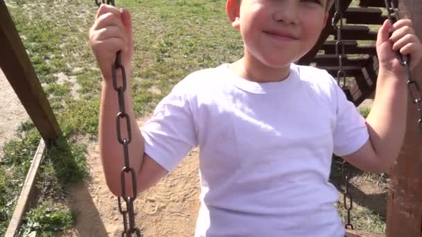 Niño feliz en un columpio en el verano — Vídeos de Stock