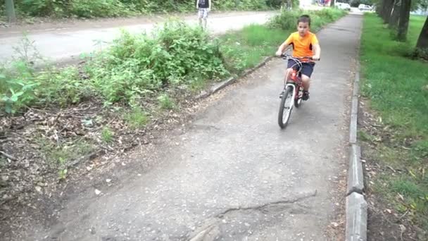 Menino monta bicicleta em foco como ele se aproxima da câmera . — Vídeo de Stock