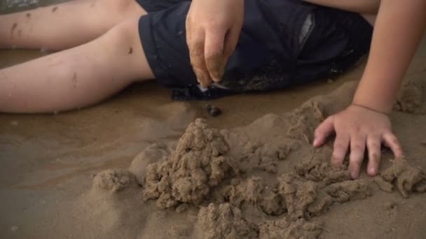 Szczęśliwy chłopiec bawi się piasek na brzegu — Wideo stockowe