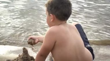 Kum ile sahilde oynarken mutlu çocuk