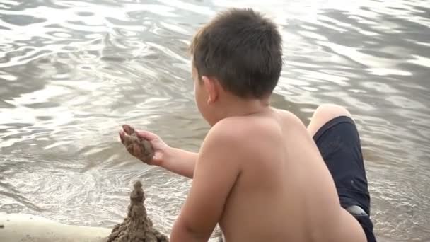 Šťastný chlapec hraje s pískem na pobřeží — Stock video