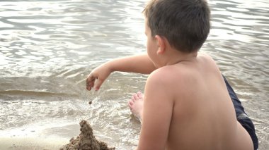 Kum ile sahilde oynarken mutlu çocuk