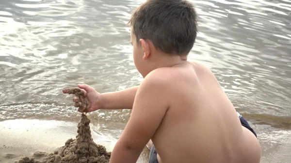 Šťastný chlapec hraje s pískem na pobřeží — Stock fotografie