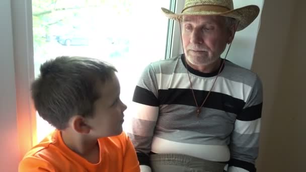 Abuelo y nieto hablando, riendo y mirando a la cámara - el anciano y el niño — Vídeo de stock