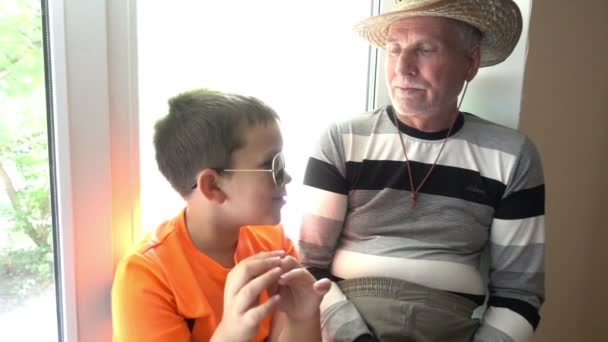 Opa en kleinzoon praten, lachen en kijken naar de camera - de oude man en het kind — Stockvideo