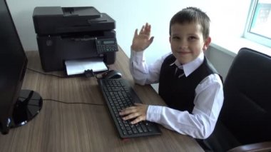 Bilgisayarda çalışan bir çocuk. Ofiste iş adamı yapar