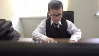 Bilgisayarda çalışan bir çocuk. Ofiste iş adamı yapar