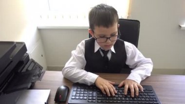 Bilgisayarda çalışan bir çocuk. Ofiste iş adamı yapar