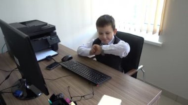 Bilgisayarda çalışan bir çocuk. Ofiste iş adamı yapar