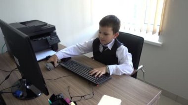 Bilgisayarda çalışan bir çocuk. Ofiste iş adamı yapar