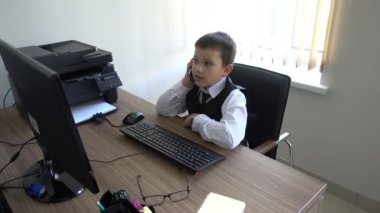 Bilgisayarda çalışan bir çocuk. Ofiste iş adamı yapar