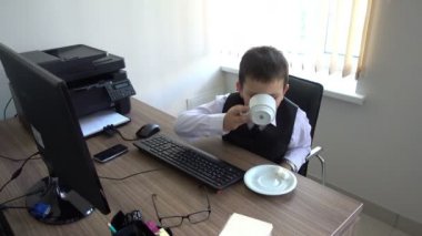 Bilgisayarda çalışan bir çocuk. Ofiste iş adamı yapar