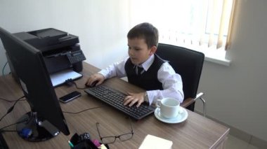 Bilgisayarda çalışan bir çocuk. Ofiste iş adamı yapar