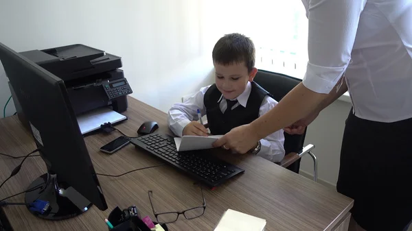 Boy depicts a businessman behind a Desk in the office, boy in office review documents — Stock Photo, Image