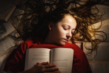 Bir yığın kitap üzerinde uyuyan kız