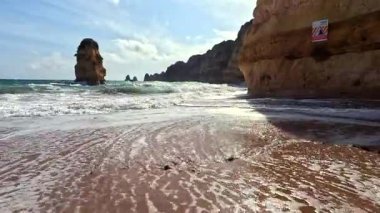 Güney Portekiz 'in Algarve Faro Bölgesi' ndeki Praia Dona Ana Sahili 'ndeki Dalgalar ve Kayalıklar. 4K GoPro Seyahat Görüntüsü