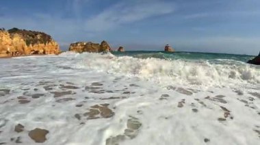 Praia Dona Ana Sahili Lagos 'tan el kamerasıyla çekilmiş görüntüler. Güney Portekiz Sahili Yüzme Denizi. Güneşli bir günde Büyük Sörf Dalgaları 4K POV Görüntüsü.