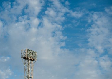 Sahanın üzerinde projektörler ve arka planda bulutlar.