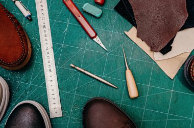 Ayakkabı yapımı aletler. Cetvel, tül, bıçak, boya ve deri, ayakkabı. Yeşil arkaplan üst görünüm kopyalama alanı