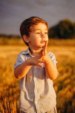 Yazın batan güneşin sıcacık ışınlarında tarlada oynayan duygusal küçük sevimli çocuk. Çocukluk kavramı.