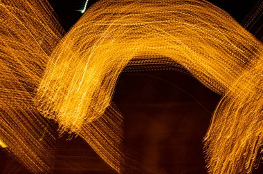 Dijital ışıkların hızı. Parlak turuncu neon bir yörünge boyunca hızla hareket eden ışık akışları. Flaşlı hızlı enerji dalgaları. Siyah arkaplanda girdap izi.