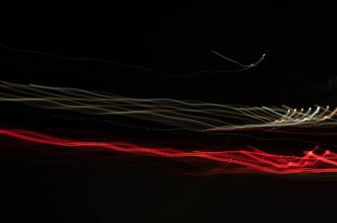 Dijital ışıkların hızı. Parlak kırmızı ve beyaz neon bir yörünge boyunca hızla hareket eden ışık akışları. Flaşlı hızlı enerji dalgaları. Siyah arkaplanda girdap izi.