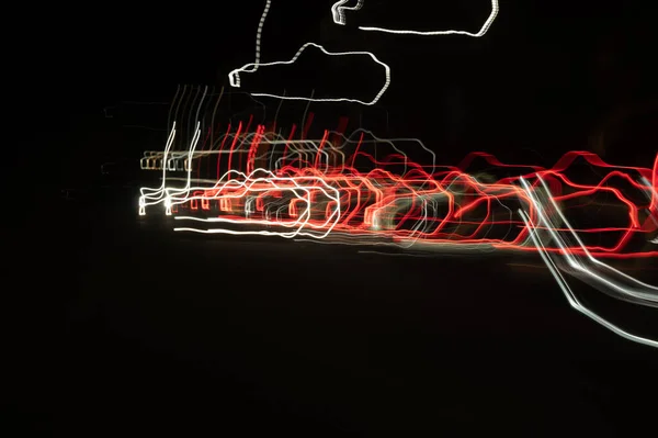 Speed of digital lights in motion. Bright red and white neon glowing fast moving streams of light, along a trajectory. Fast energy flying wave line with flash lights. Swirl trace path on black background.