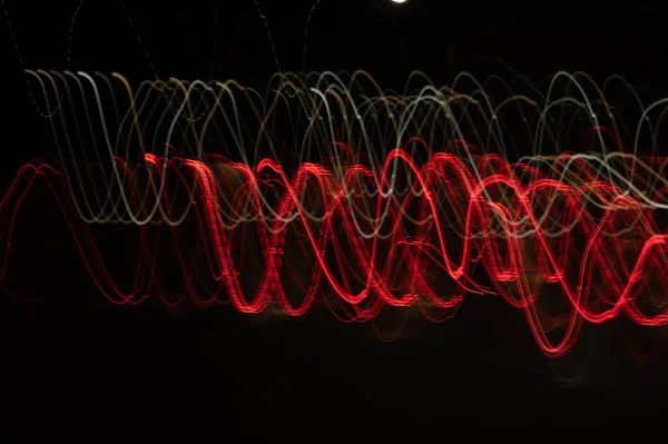 Speed of digital lights in motion. Bright red and white neon glowing fast moving streams of light, along a trajectory. Fast energy flying wave line with flash lights. Swirl trace path on black background.