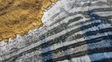 Mavi buzun yüzeyindeki çatlaklar. Şehirlerde donmuş göl. Kasabanın gölü olan kış havası. Kar yağıyordu. Dron 'dan muhteşem sabah manzarası. Seyahat konsepti arka planı.