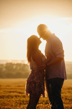 Romantik ilişki kavramı. Gün batımında buğday tarlasında el ele tutuşan bir çift. Sonbahar mevsimi. 