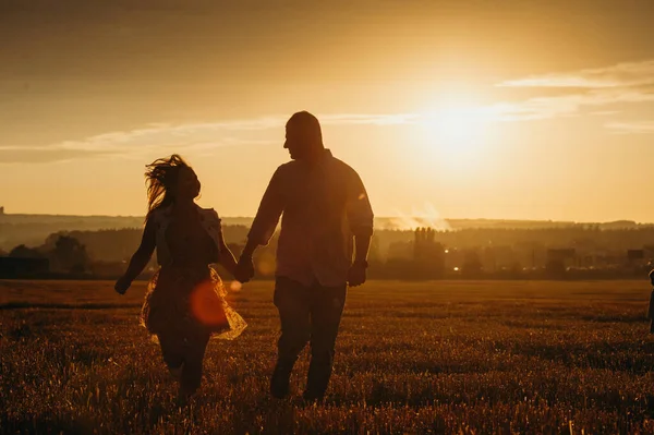 恋爱关系的概念 一对夫妇牵着手在阳光下的落日下在麦田里奔跑 秋季季节 — 图库照片