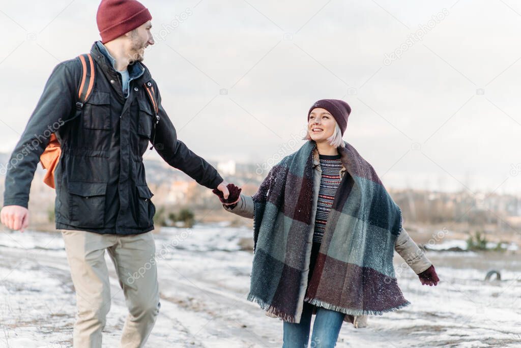 Cool valentine. Happy loving couple walking in snowy winter field, spending Christmas vacation together. Outdoor seasonal activities. Lifestyle capture.