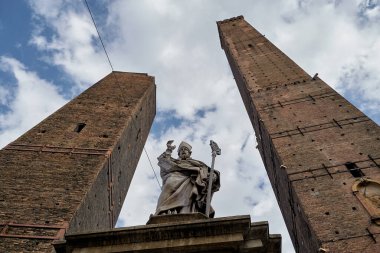 BOLOGNA, İtalya - 30 EYLÜL 2019: Torre Garisenda ve Torre Degli Asinelli 'nin Torri' deki kuleleri. Yani iki kule. Heykel De Hl. Petronius.